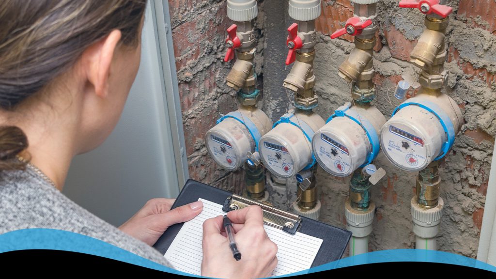 A woman with a clipboard taking notes on a water meter reading.