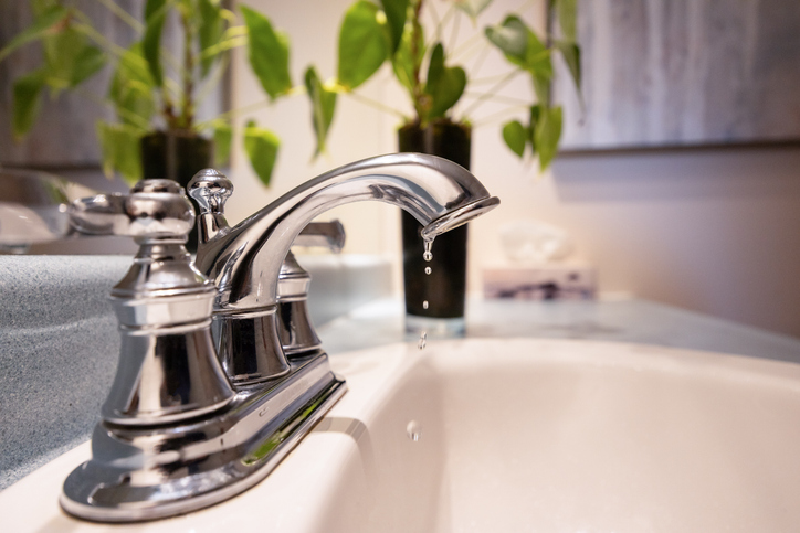 A bathroom faucet slowly dripping water, highlighting a common plumbing issue