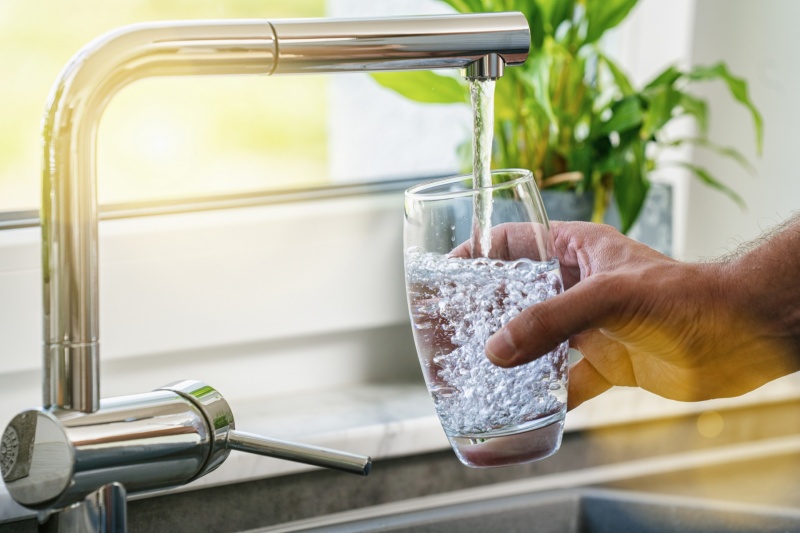 A man filling a glass with clean water from their faucet